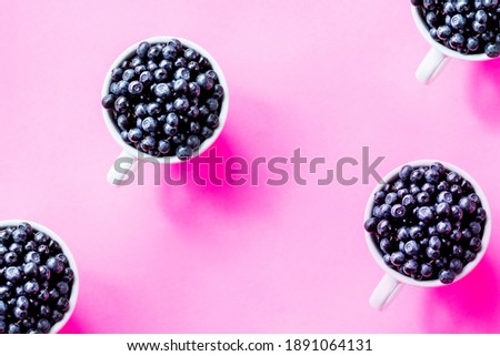 Creative pattern of blueberries in white cups on bright background.Seamless pattern Cup of berries. Fresh sweet fruits. Food background. Summer snack.raw organic blueberry in a mug