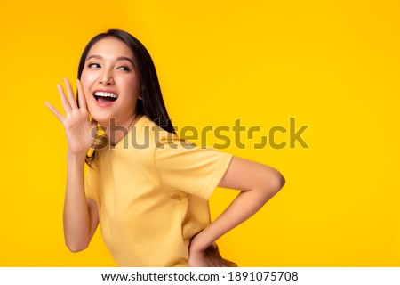Surprised happy beauty asian woman looking copy space in excitement Expressive facial expressions Presenting some product. Beautiful girl act like a telling secret Isolated on yellow background