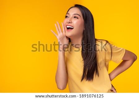 Surprised happy beauty asian woman looking copy space in excitement. Expressive facial expressions. Presenting some product. Beautiful girl act like a telling someone Isolated on yellow background
