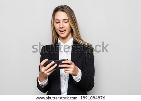 A business woman in a black suit with a smile and typing on a tablet mobile phone. Portrait on white background with studio light.