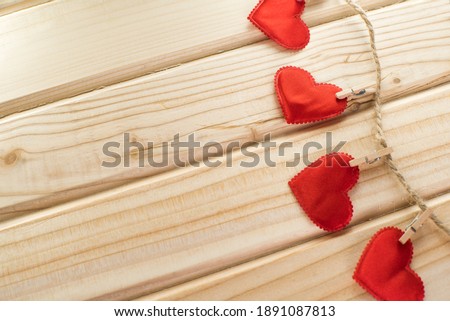 red hearts decoration hanging on a rope, wooden background. Valentine's Day. Place for text.