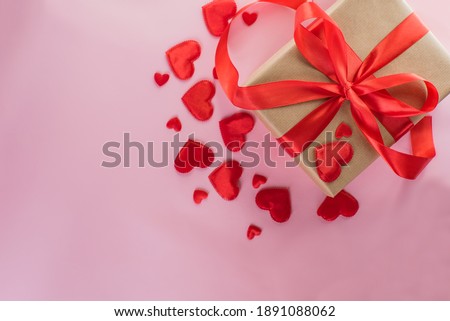 craft gift tied with a red ribbon with hearts on a pink background. Valentines day.