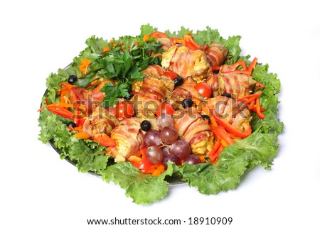 Quail rolls in bacon served with fruit, vegetables and greens over white background