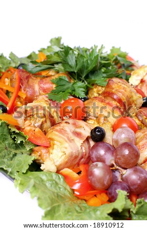 Quail rolls in bacon served with fruit, vegetables and greens over white background