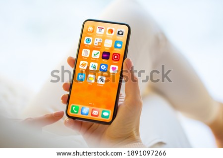 Woman using mobile phone with home screen opened showing different everyday app icons Royalty-Free Stock Photo #1891097266