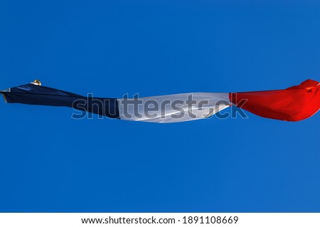 Closeup of a national French flag blowing in the wind on clear blue sky, photographed from below (low angle view).
