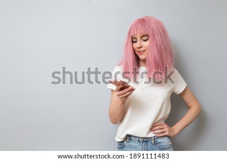 Smiling pink-haired girl writing message on smartphone. Online learning, internet surfing, online communication concept