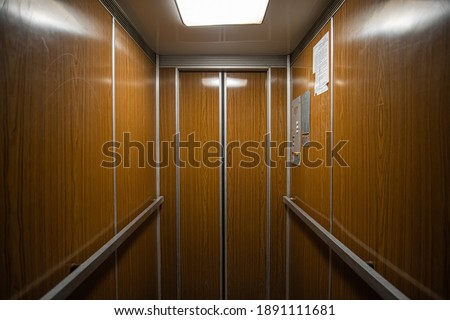 Interior inside a closed clean old Soviet elevator car lined with wood. Royalty-Free Stock Photo #1891111681