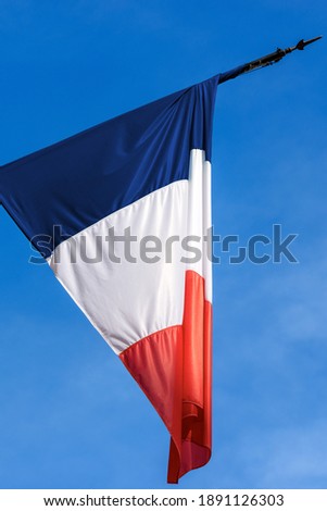 Closeup of a national French flag and flagpole on clear blue sky, photographed from below (low angle view).