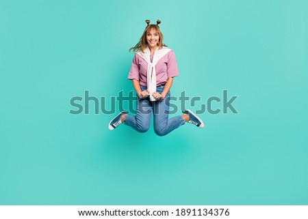 Full size photo of young lovely pretty smiling cheerful girl with sweater on shoulders jumping isolated on teal color background