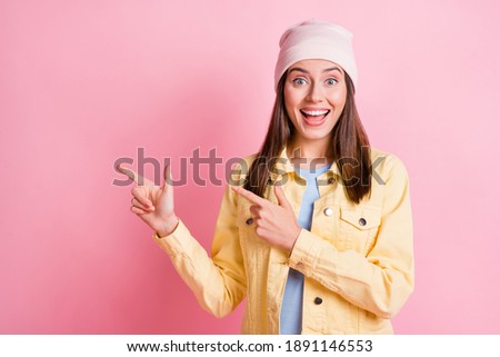 Photo of excited brown haired young woman point empty space promotion wear yellow jacket hat isolated on pink color background