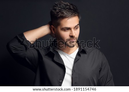 Handsome man with stylish hairdo on dark background Royalty-Free Stock Photo #1891154746