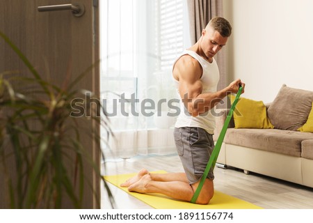 Young and muscular man during home workout with a resistance rubber bands