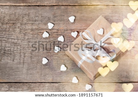 Valentine's day gift box. Gift decorated with white heart shaped chandies. Valentine's day gift on wooden background.