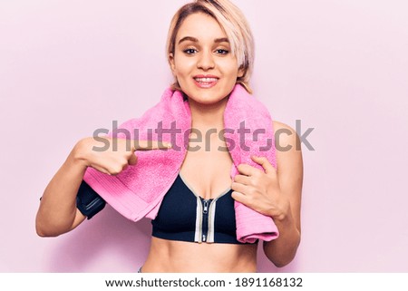 Young beautiful blonde woman wearing sportswear and towel smiling happy pointing with hand and finger 