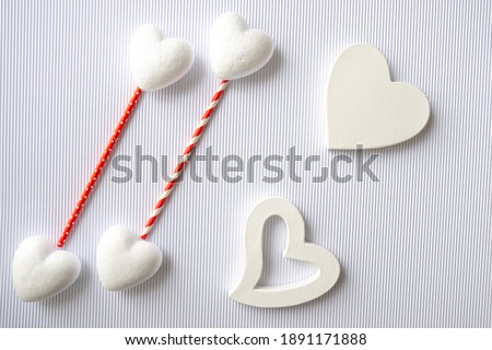 On Valentine's Day February 14, flatleys on the spruce background of 4 white little hearts of soedines with red bright tubes and two white big hearts.
