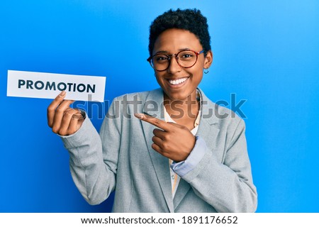 Young african american girl holding sale poster smiling happy pointing with hand and finger 