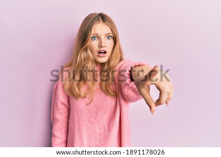 Beautiful young caucasian girl wearing casual clothes pointing with finger surprised ahead, open mouth amazed expression, something on the front 