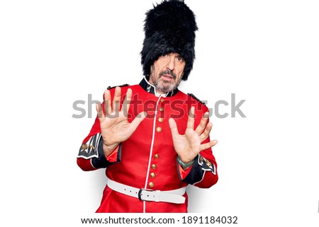 Middle age handsome wales guard man wearing traditional uniform over white background Moving away hands palms showing refusal and denial with afraid and disgusting expression. Stop and forbidden.
