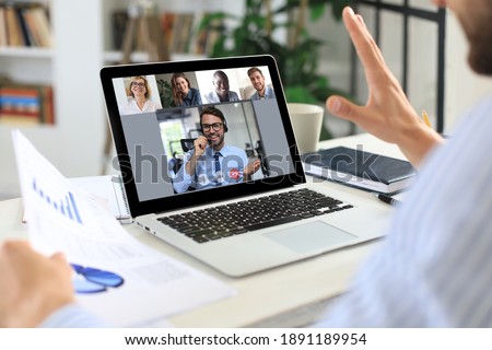 Businessman video conferencing with colleague on laptop in office.