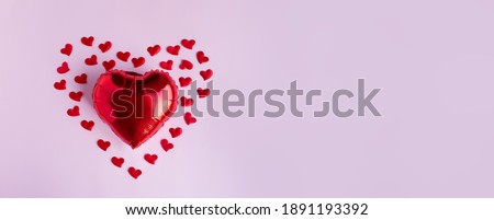 Red balloons in shape of heart,and many small hearts around, on pale pink background. Valentines day concept. Banner, copy space