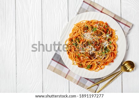 pasta spaghetti alla norma on a white plate on a white textured wooden table with golden spoon and fork, italian cuisine, horizontal view from above, flat lay, free space