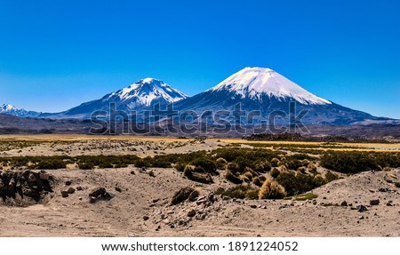 Parinacota and Pomerape Volcanoes above the horizon over Cotacotani lagoons waters an awesome and dramatic landscape inside Lauca National Park, Chile