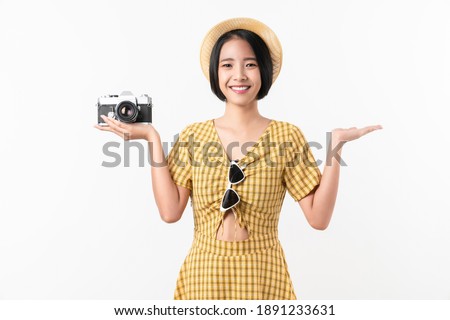 Young smiling Asian woman tourist holding camera and looking to copy space on white background.