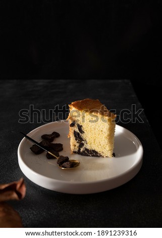 Vanilla chiffon slice cake with oreo. made in Indonesia, soft texture and delicious taste. On white plate and black background. Selective Focus