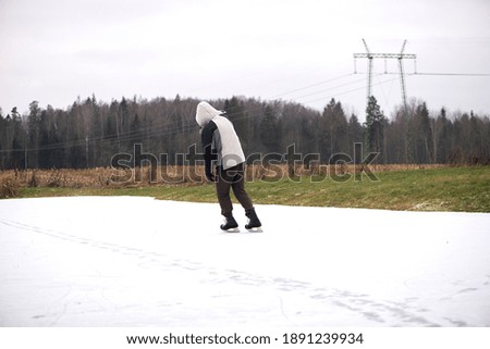 Rear view on middle aged man in casual clothing ice skating outdoors on a lake