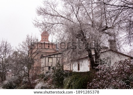 Small stone church with old house surrounded by snow. Winter landscape. Ávila, Spain.