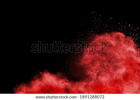 Abstract red powder explosion on black background. Freeze motion of red  dust splattered.