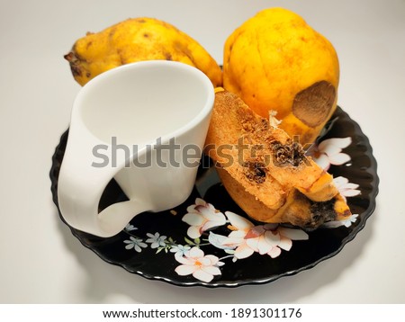 some quinces and a white empty cup on a black plate 
