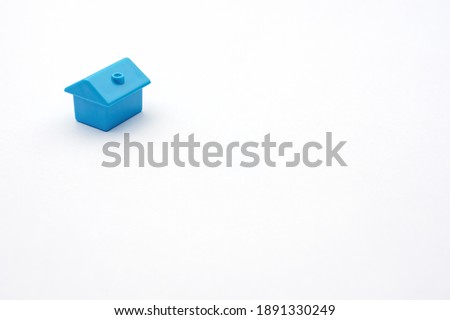 Simply minimal design one single blue toy miniature or model cottage house on white background and copy space. Purchasing or buying eco house or rental of property and constructing new small cosy home