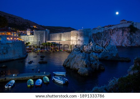 Night Photography of Dubrovniks Canoe and Ship Port Next to Its Walls with A Full Moon in the Background