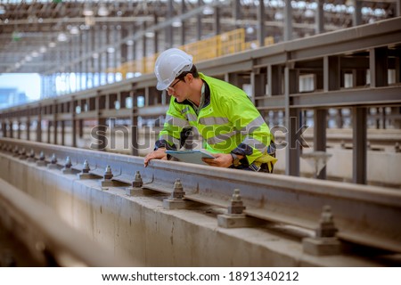 Engineer railway under inspection and checking construction process train work shop and railroad station .Engineer wearing safety uniform and helmet by holding document in work. Royalty-Free Stock Photo #1891340212
