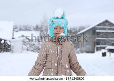 natural light. snowy winter. A child in a winter jacket and a knitted hat throws snow up