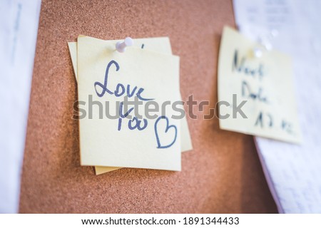 Close up of pinned note “Love you” on cork board