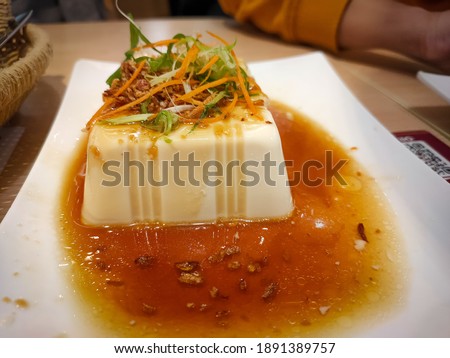 Picture of Tofu cake with chicken sauce in blurry background.