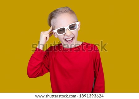 a child in 3D glasses puts his hand to his temple and shows pain in his head