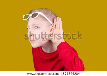 a child in 3D glasses puts his hand to his ear and tries to hear something