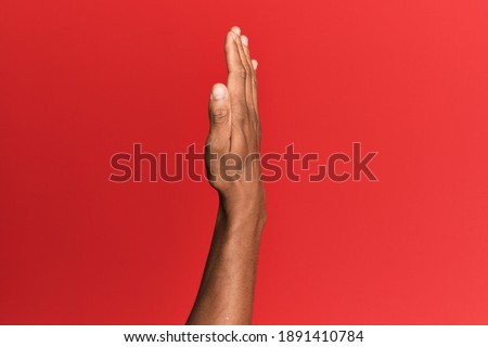 Hand of hispanic man over red isolated background showing the side of stretched hand, pushing and doing stop gesture 