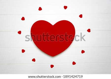 Big red heart surrounded with many little hearts on white wooden board as romantic background. Valentine Day, Women`s Day, Mothers Day greeting card or invitation for wedding with copy space.