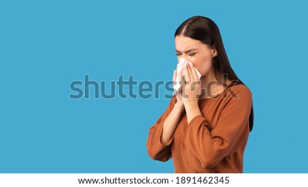 Cold And Flu. Sick Woman Blowing Runny Nose In Paper Tissue Having Rhinitis Symptom Standing On Blue Studio Background. Lady Sneezing Suffering From Allergy. Panorama, Empty Space Royalty-Free Stock Photo #1891462345