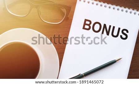 BONUS - text on paper with cup of coffee and glasses on wooden background in sinlight.