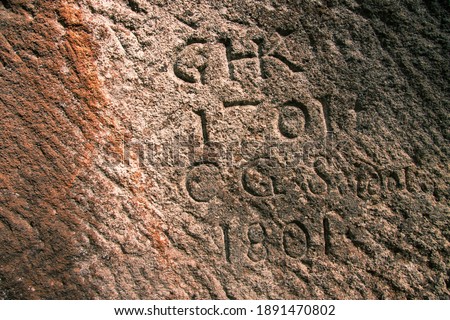 Very old dates carved into a rock face.