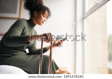 Woman With Suitcase Checking Out Of Boutique Hotel Waiting For Taxi Ordered On Mobile Phone App Royalty-Free Stock Photo #1891478185
