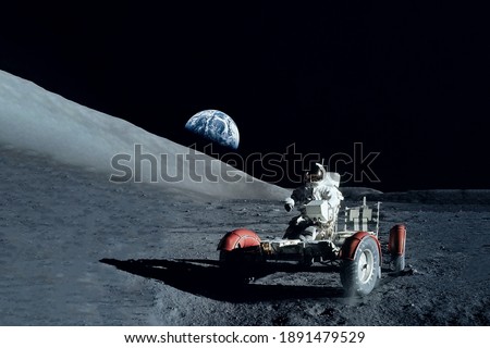 Astronaut near the moon rover on the moon. With land on the horizon. Elements of this image were furnished by NASA. High quality photo
