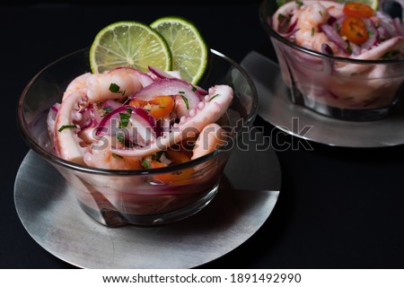 Typical Peruvian food, ceviche with squid, shrimp and white fish with purple onion and a good tiger's milk. Served in a glass container on dark background. Gourmet concept, elegance