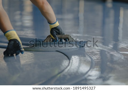 The worker applies gray epoxy resin to the new floor Royalty-Free Stock Photo #1891495327